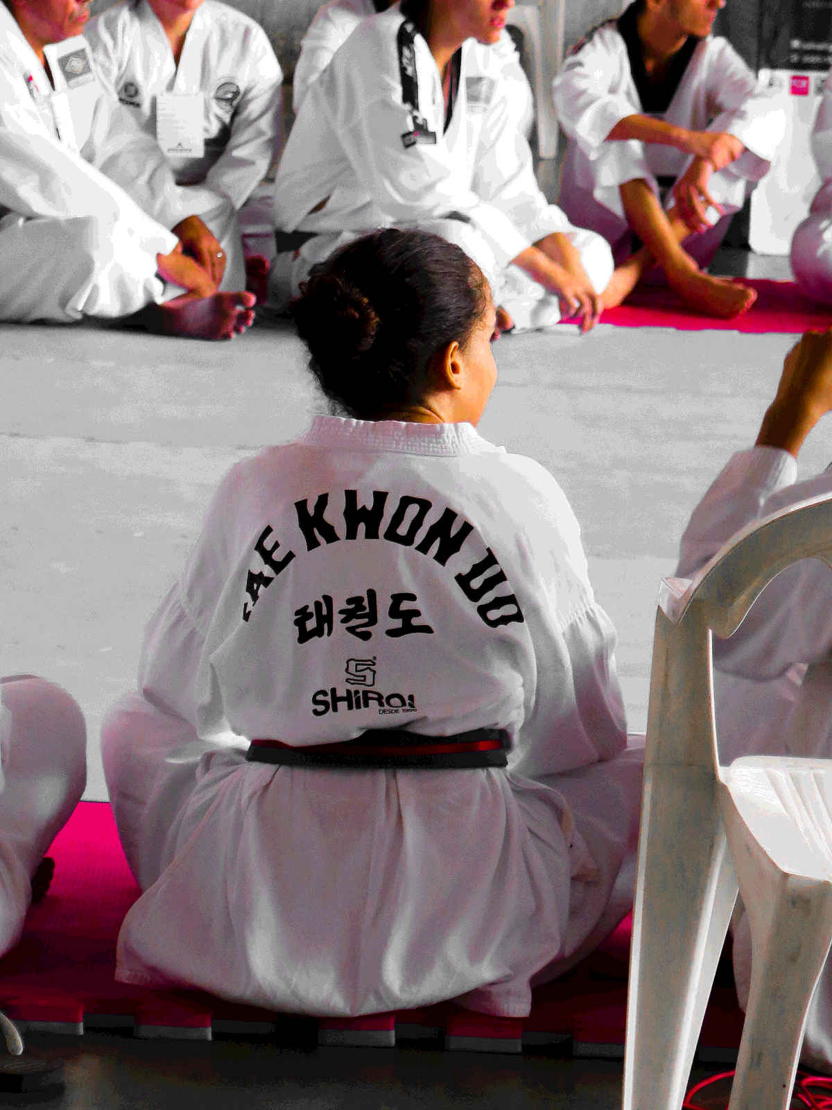 Taekwondo students sit listening to their instructor